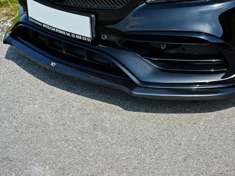 The front bumper of a sleek, black car with intricate vents and a glossy finish sits on a sunlit asphalt road. Text: "Mercedes-Benz INTER-CAR RYBNIK tel. 32 888 53 01".