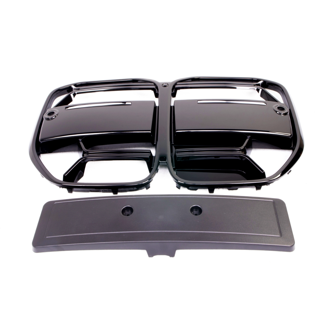 Black plastic grille with two rectangular openings placed above a rectangular cover featuring two circular holes, on a plain white background.