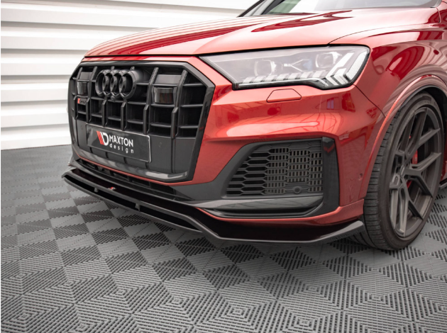A red car with a distinctive black grille and logo is parked on a patterned gray floor. The context is a modern showroom with white, ribbed walls. Text reads "MAXTON design."