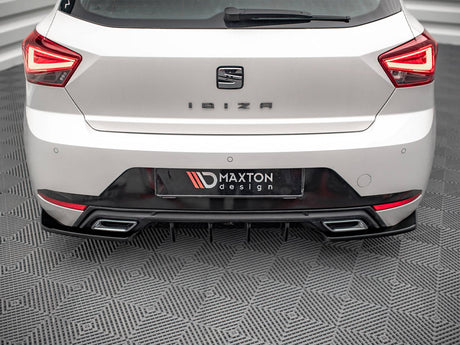A white car's rear, labeled "IBIZA," is stationary on a patterned floor. The license plate reads "MAXTON design," surrounded by distinctive taillights and a dual exhaust.