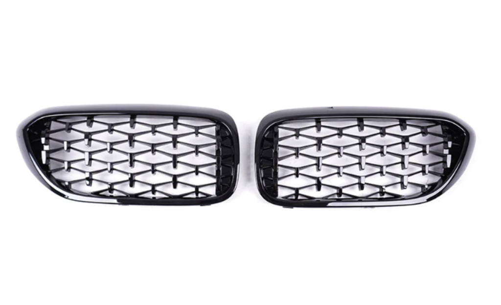 Two black, glossy car grilles feature a diamond-patterned mesh. They are positioned side by side against a plain white background, showcasing their shiny surface and symmetrical design.