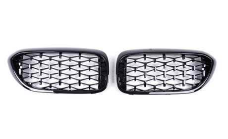 Two black, glossy car grilles feature a diamond-patterned mesh. They are positioned side by side against a plain white background, showcasing their shiny surface and symmetrical design.