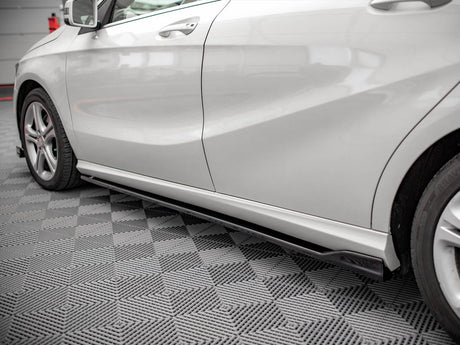 White car parked indoors, highlighting its sleek side profile with aerodynamic contours. The floor has a gray geometric patterned design, and the vehicle rests in a well-lit garage setting.