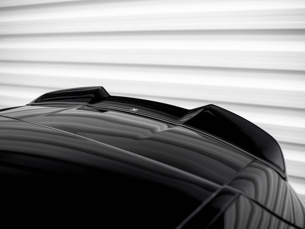 A shiny black car roof features an aerodynamic fin. It's positioned against a blurred, horizontally-striped, white background, creating a sleek and modern appearance.