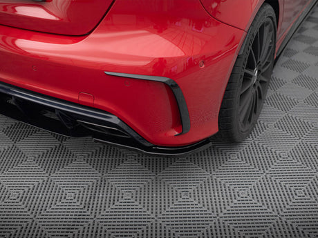 A red car's rear bumper and wheel are shown on a textured, gray, diamond-patterned mat, emphasizing sleek design and detailing.