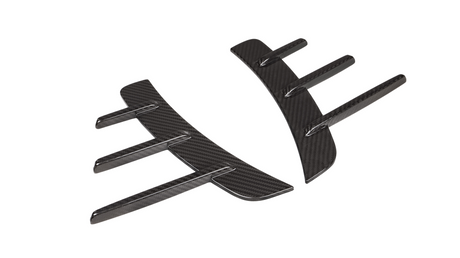 Two black carbon fiber car accessories with curved shapes and protruding fins are positioned parallel to each other on a plain white background.