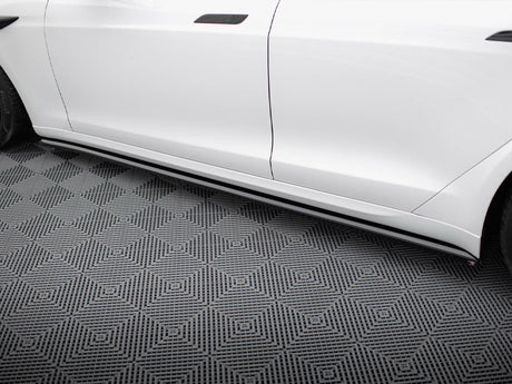 White car side, featuring sleek side skirts, parked on a patterned floor with geometric diamond shapes, creating a modern, polished appearance.