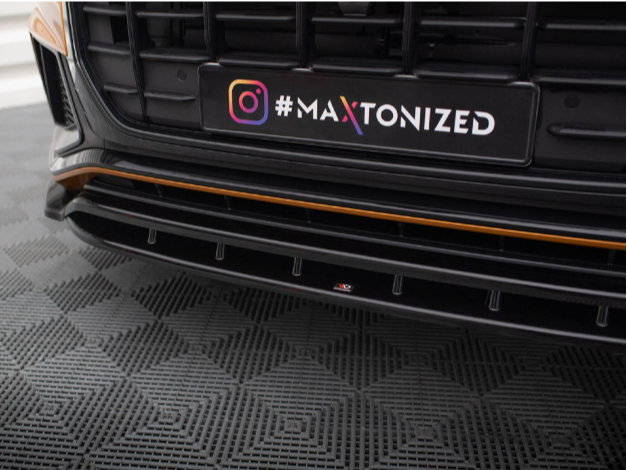 Car bumper with a customized black grille featuring the text "MA XTONIZED" and an Instagram icon, displayed on a textured checkered-patterned floor.