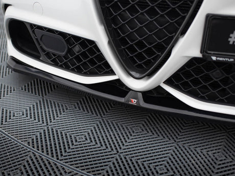 Car grille with a V-shaped design and black mesh pattern, positioned close to the ground. The left side shows a sensor. The floor has a textured geometric pattern.