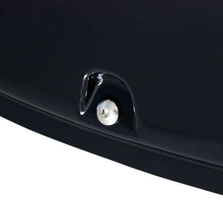 A metallic button surrounded by glossy black material is embedded in a dark, smooth surface, suggesting part of a vehicle's exterior.