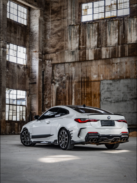 A white sports car is parked in an abandoned warehouse with large, rusted windows and a gritty, industrial atmosphere.