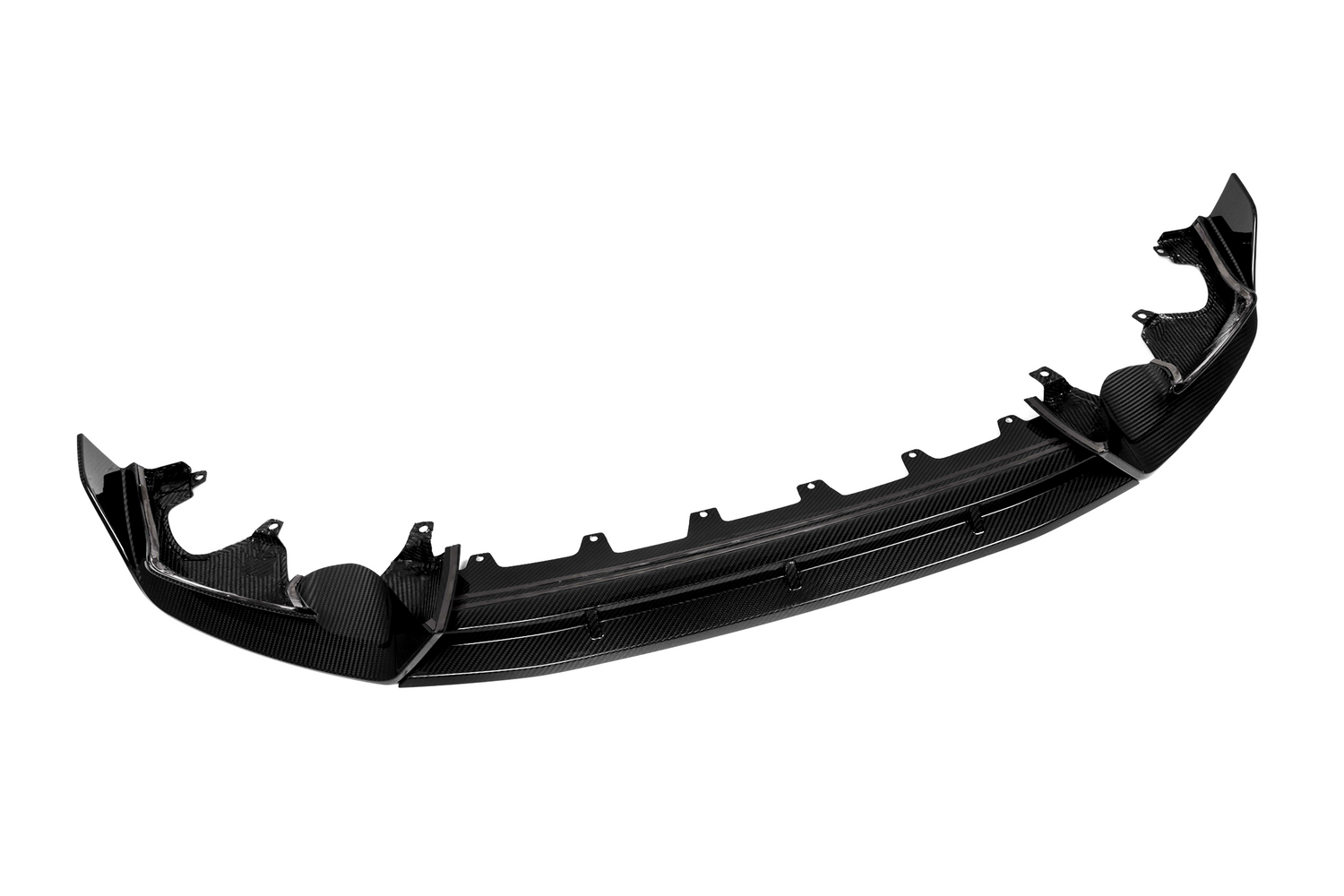 A glossy, carbon fiber car bumper lip is shown from the front, detached and isolated on a white background, highlighting its aerodynamic design and mounting features.