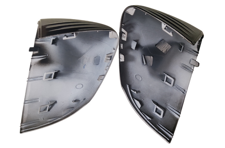 Two black plastic automotive parts, each featuring multiple clips and grooves, are placed side by side. The parts have a curved shape with textures and patterns on their surfaces.