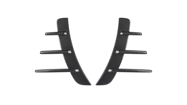 Two black carbon fiber pieces with three horizontal fins each are symmetrically aligned. They are set against a plain white background, suggesting automotive parts.