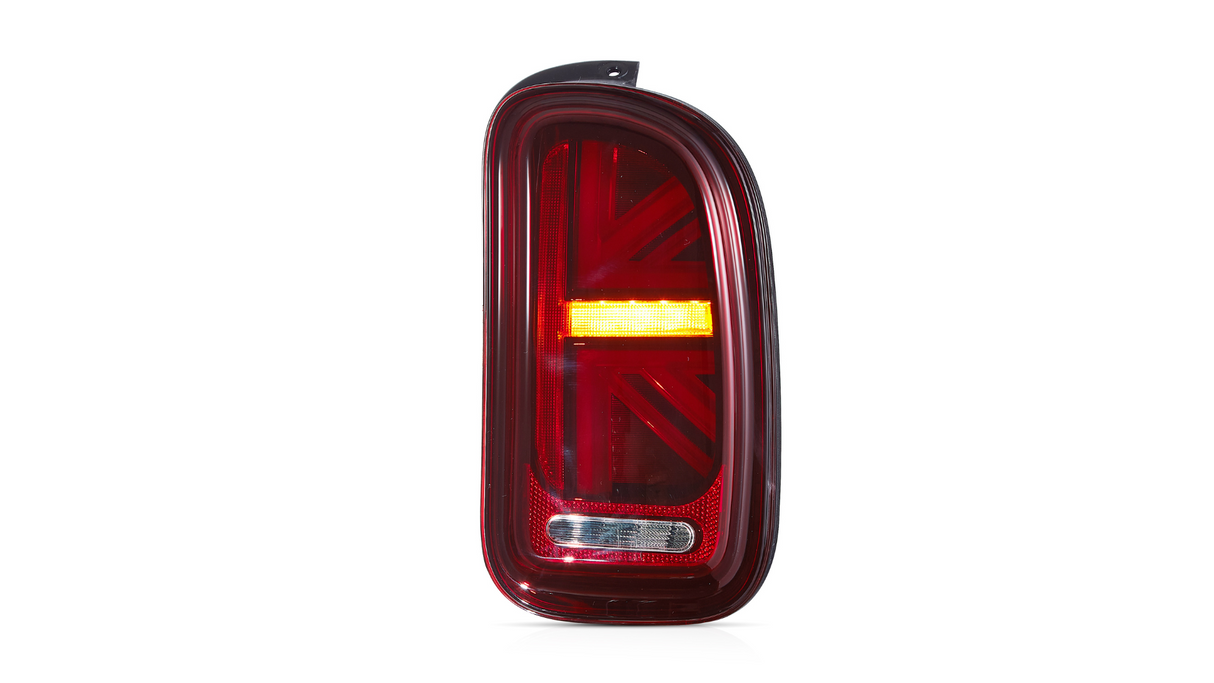 A red car taillight features a distinctive Union Jack pattern and an illuminated orange strip, set against a plain white background.