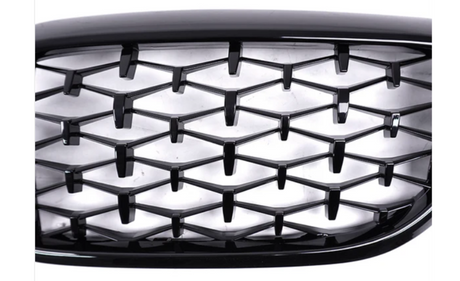 Honeycomb-patterned black grille in a car front view, with a glossy finish. The grille has a three-dimensional design, appearing against a bright, neutral background. No text is present.