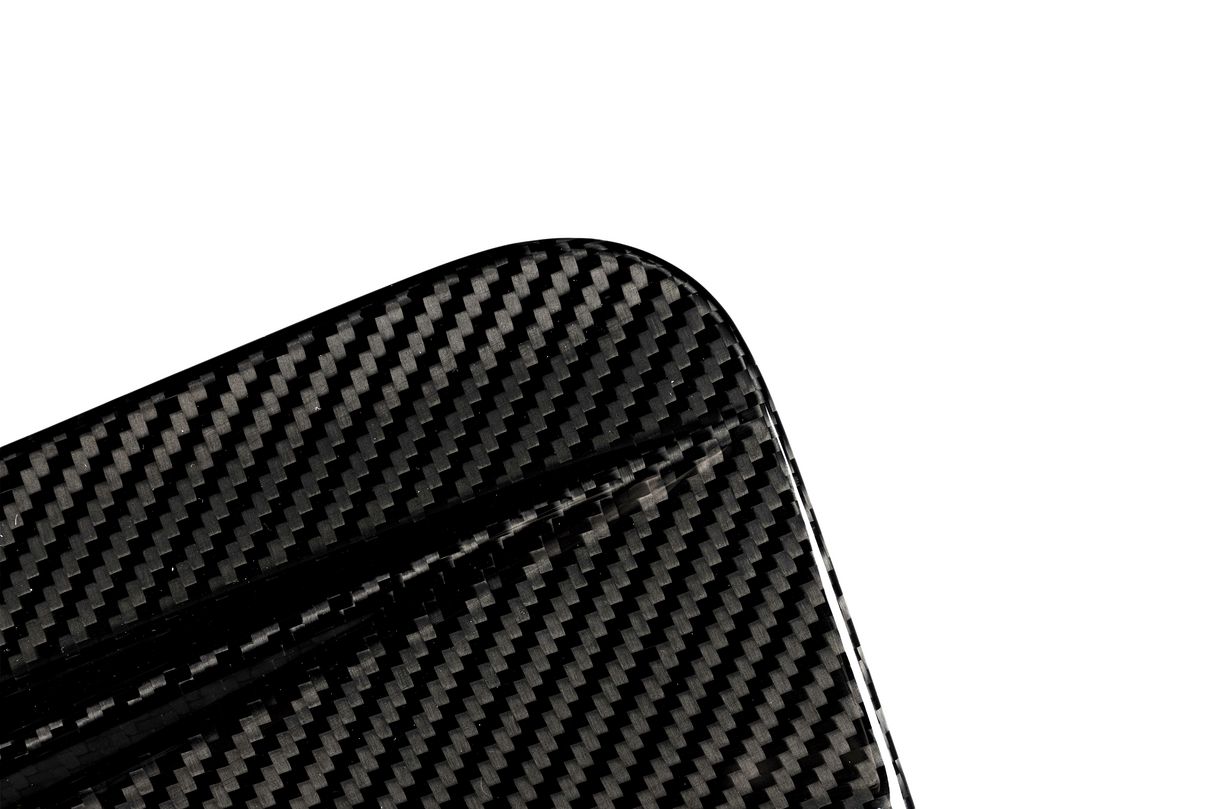 A close-up of a carbon fiber object with a visible textured pattern, featuring a rounded corner, set against a plain white background.