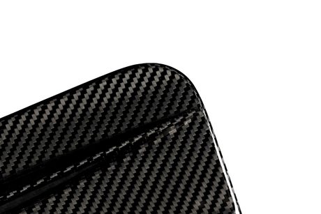 A close-up of a carbon fiber object with a visible textured pattern, featuring a rounded corner, set against a plain white background.