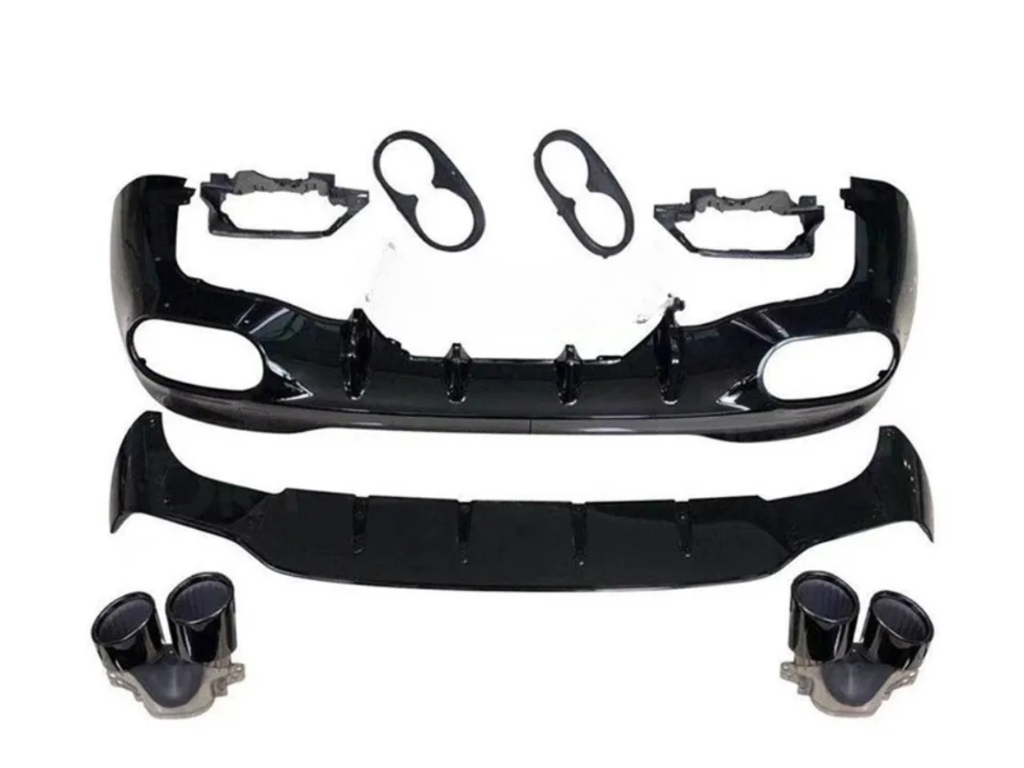 A disassembled car body kit includes a black front bumper with vent openings, a lower splitter, light bezels, and dual exhaust tips, arranged on a plain white background.