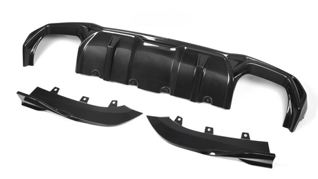 Carbon fiber car diffuser components lie on a white background. The main piece, with multiple ridges, is accompanied by two curved side parts, each featuring mounting brackets.