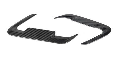 Carbon fiber steering wheel trim pieces, curved and glossy, rest on a plain white background.