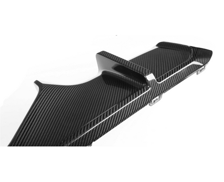 A carbon fiber car rear diffuser with fins is angled upward, showcasing its sleek, aerodynamic design. It is positioned against a plain white background, highlighting its textured surface.