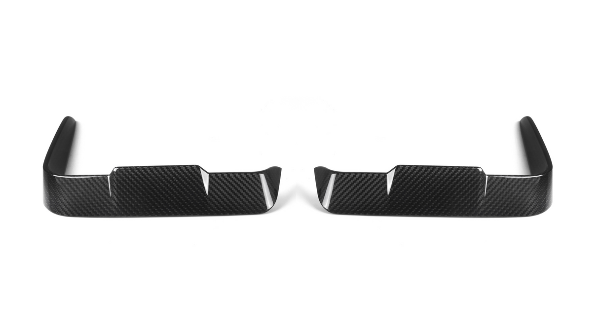 Two black carbon fiber car trim pieces lie side by side, each featuring a sleek, angular design with vertical slits, set against a plain white background.