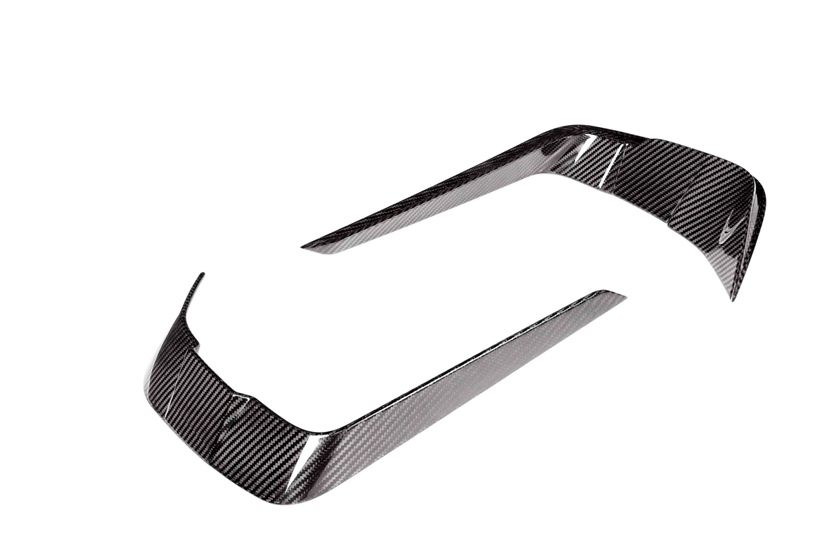 Two curved carbon fiber trim pieces, reflecting light, positioned apart on a white background. They are designed for vehicle detailing.