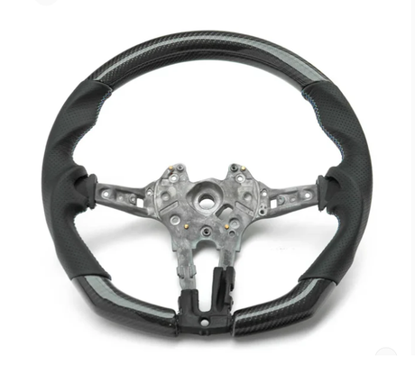 A partially assembled car steering wheel is shown, featuring a metallic central frame with exposed wiring, surrounded by a two-tone black and grey perforated leather grip, against a plain white background.