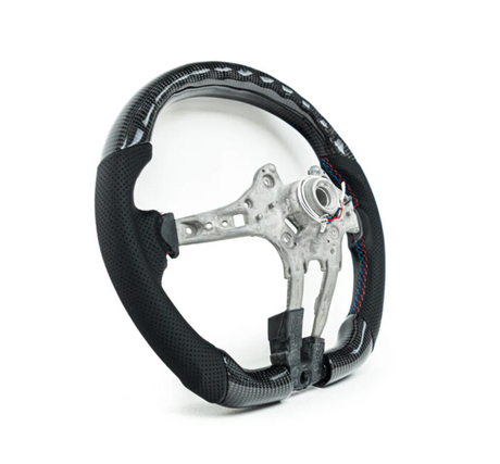 A carbon fiber car steering wheel frame with black perforated grips sits on a plain white background, showcasing exposed metal structure and colorful stitching on the grips.