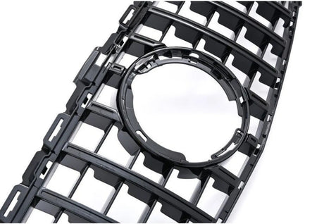 A black plastic grille featuring a series of rectangular openings surrounds a central circular cutout, set against a plain white background.
