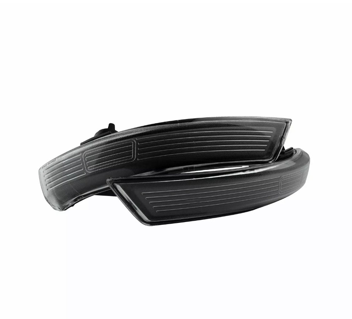 Two black, curved automotive side mirror indicators, resting on each other, have horizontal engraved lines. They are isolated on a white background, showcasing modern design elements.