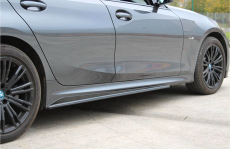 A sleek, dark gray car is parked on a concrete surface. The vehicle features modern design elements, with distinctive rims and smooth side panels, set in an open outdoor area.