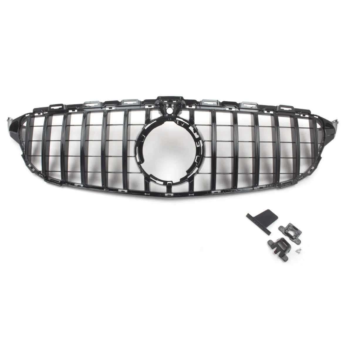 A black car grille with a circular center opening is positioned centrally; nearby, assorted mounting clips and brackets are laid out on a plain white surface.