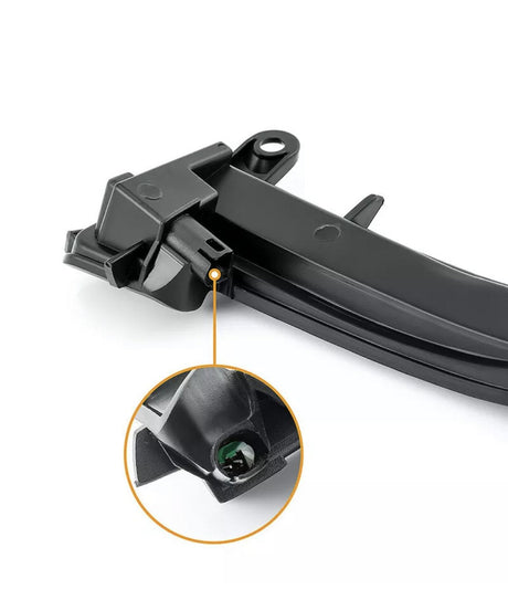 A black plastic car part positioned against a white background, with a magnified circle highlighting a small green component inside it.