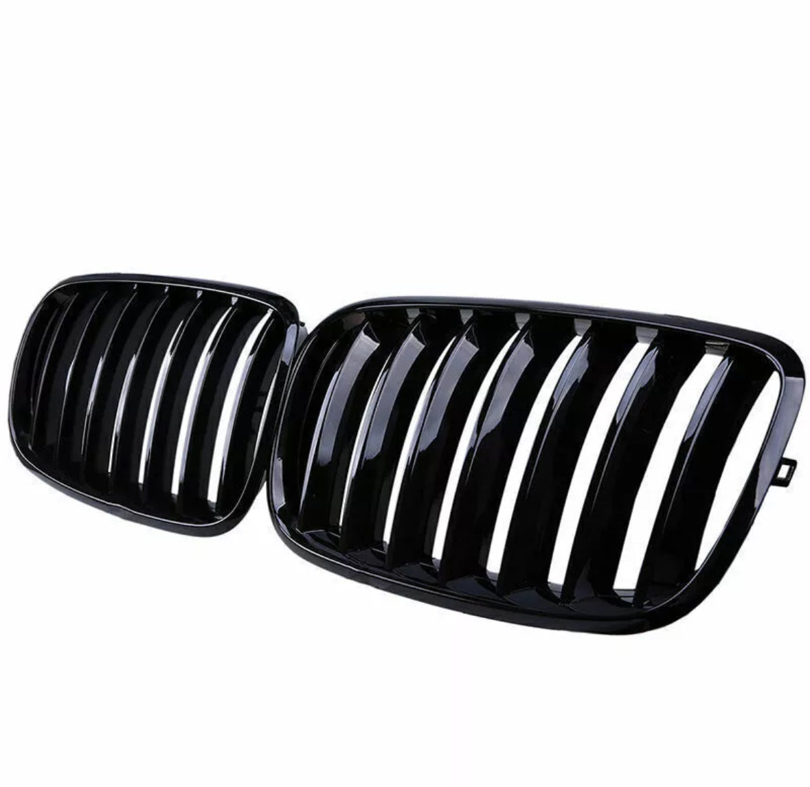 A pair of glossy black car grilles, each with vertical slats, positioned side by side against a white background.
