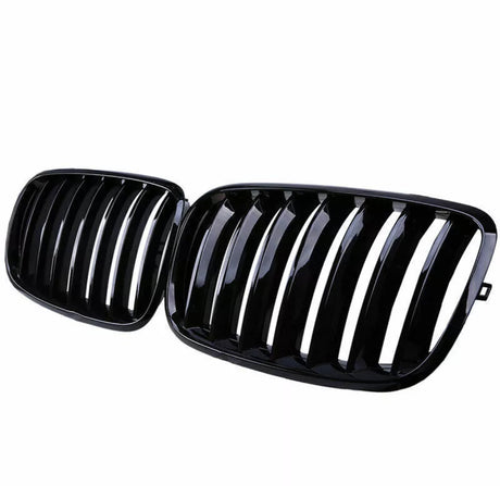 A pair of glossy black car grilles, each with vertical slats, positioned side by side against a white background.
