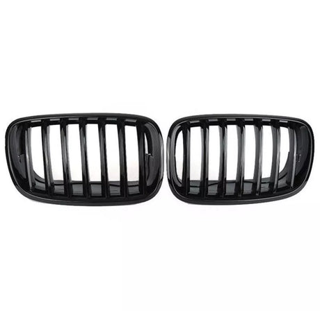 Two black car grilles with vertical slats are displayed side by side against a plain white background, showcasing a sleek automotive accessory design.