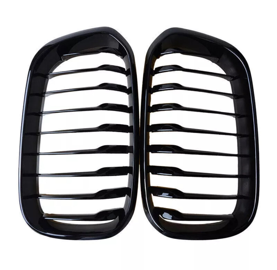 Two black kidney-shaped car grilles with horizontal slats are positioned side by side against a white background, emphasizing their glossy finish and symmetrical design.