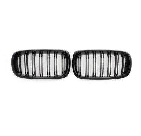 Two black car grilles, each with vertical slats, are positioned side by side against a plain white background.