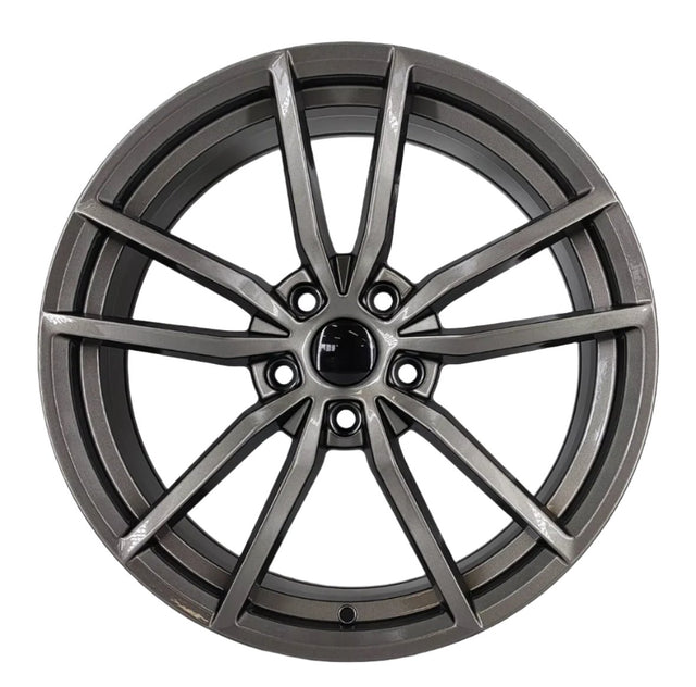 A metallic alloy wheel with intricate spoke design is centered on a plain white background, displaying a modern, sleek appearance, highlighting its detailed craftsmanship and shiny finish.