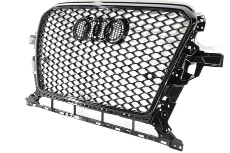 A black car grille with a honeycomb design features four interlinked rings in the center. It is suspended against a plain white background.