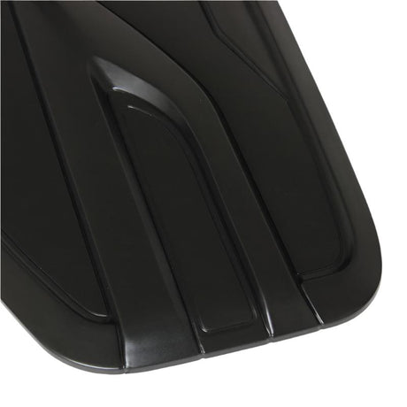 A black, sleek surface with raised, angular grooves creates a modern, aerodynamic design, possibly part of automotive equipment, shown in close-up detail, highlighting its stylish contours.