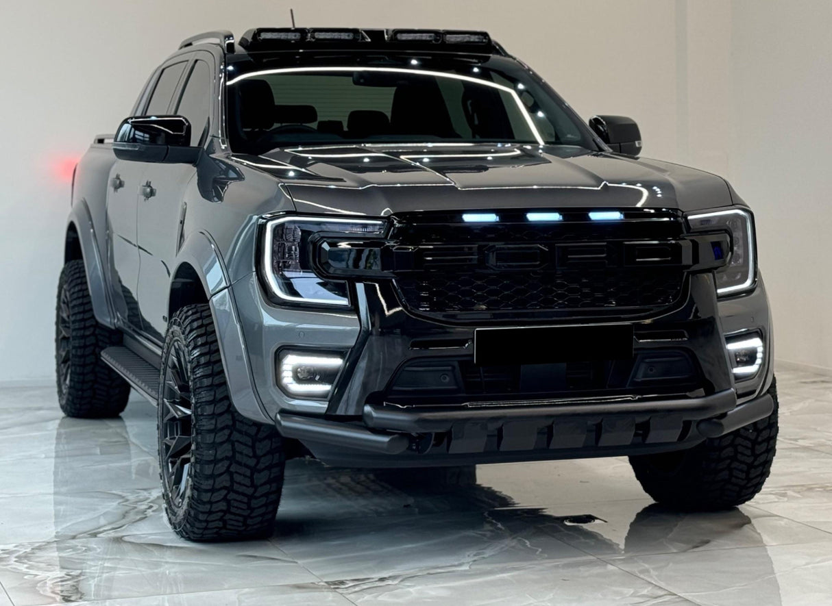 A sleek, black pickup truck with illuminated headlights and roof lights is parked indoors on a glossy tiled floor, emphasizing its rugged design.