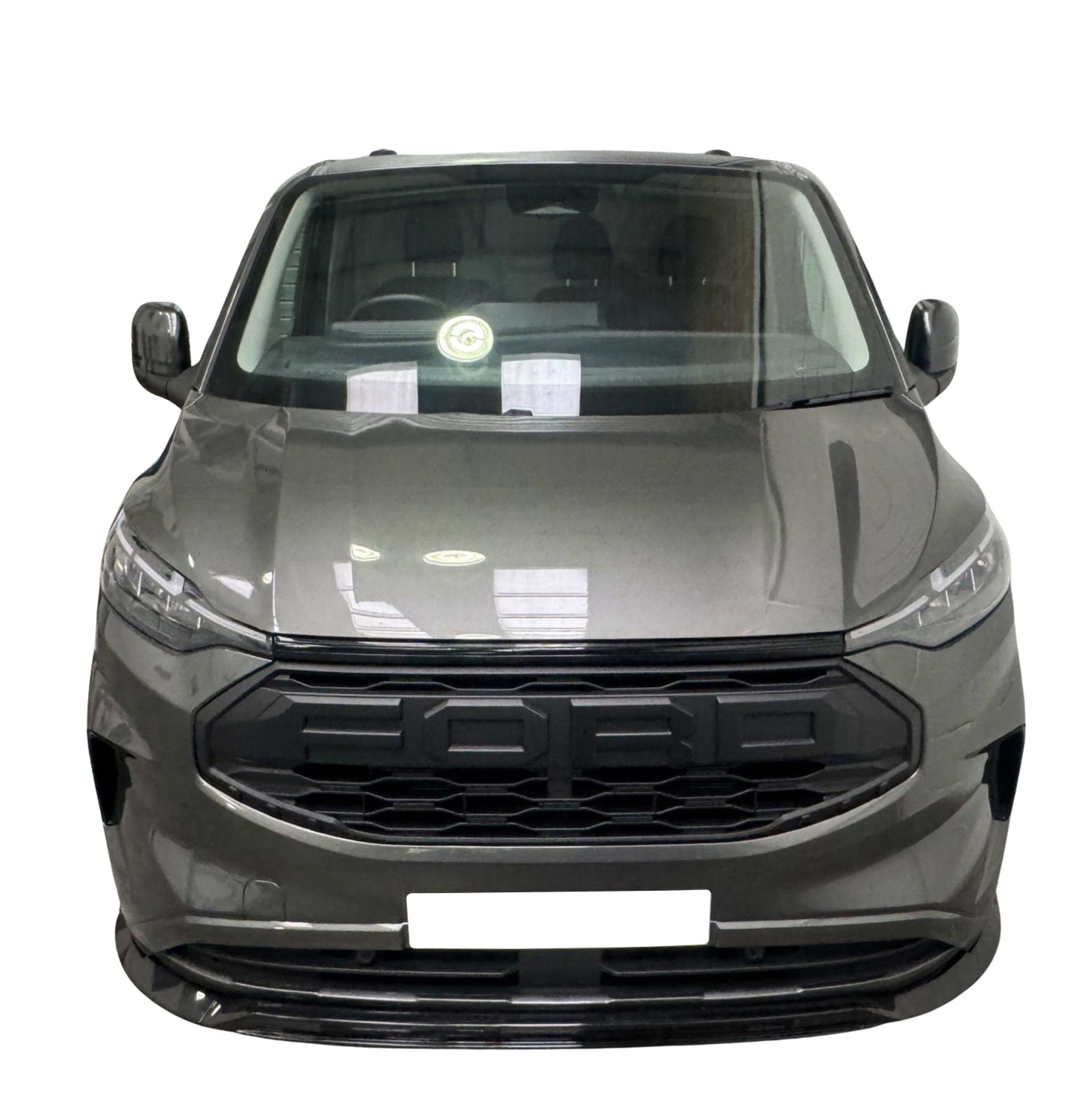 A gray vehicle stands facing forward, displaying its sleek front grille and headlights, in front of a solid black background. Reflections are visible on the windshield.