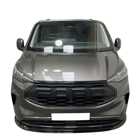 A gray vehicle stands facing forward, displaying its sleek front grille and headlights, in front of a solid black background. Reflections are visible on the windshield.