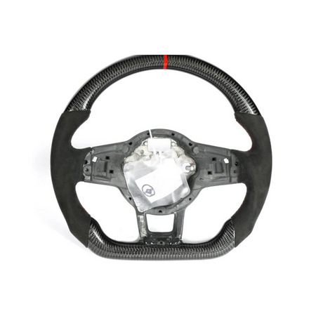A carbon fiber and suede steering wheel with a red center stripe is displayed against a plain white background. Its center is exposed, revealing inner components, and a small plastic bag is attached.