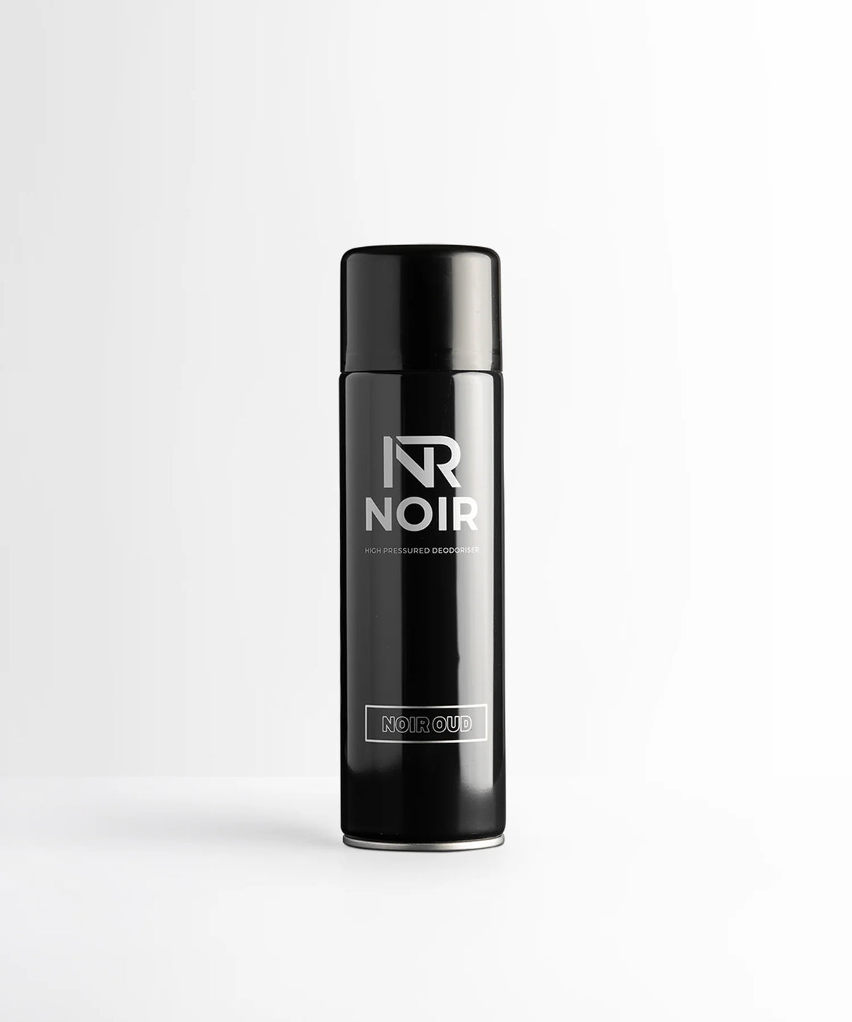 A black cylindrical deodorant can stands on a white surface. Text reads: "NR NOIR HIGH PRESSURED DEODORISER NOIR OUD." The background is a plain white wall.