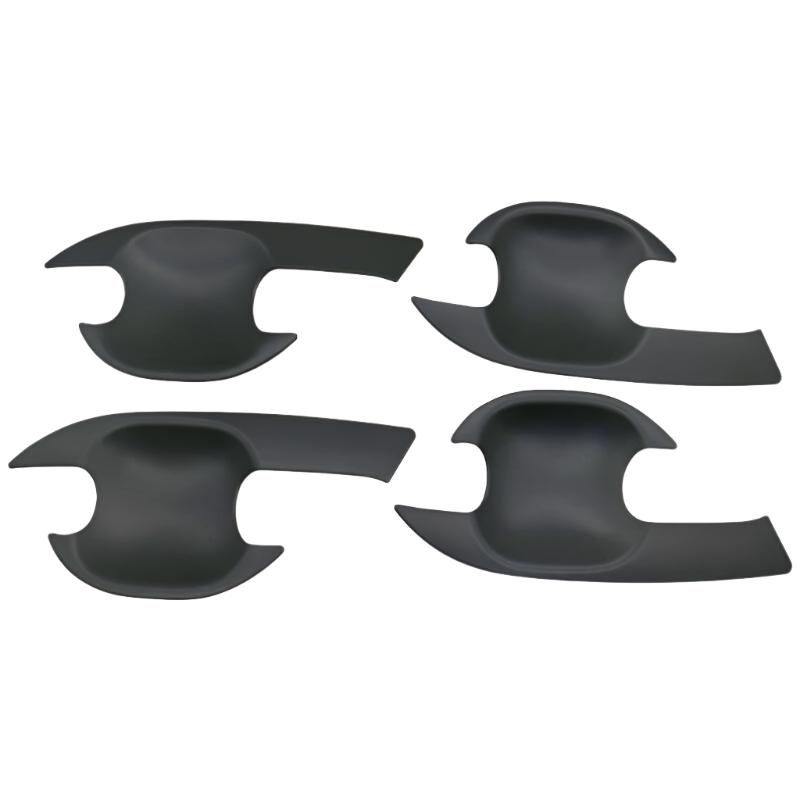 Four black, curved, plastic car door handle covers are positioned symmetrically on a plain background. They have an ergonomic design with cutouts for easy installation.