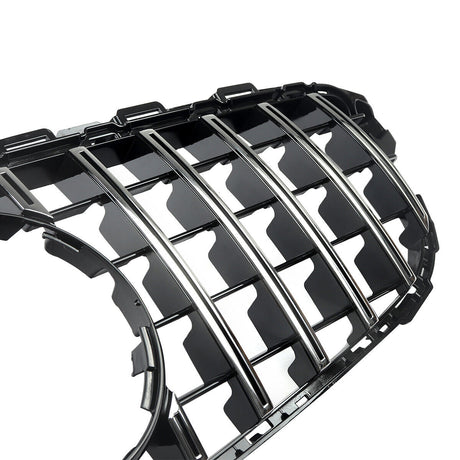 A shiny black car grille with vertical chrome slats, designed for vehicle front-end placement, lies against a white background, emphasizing its sleek, reflective surfaces and intricate detailing.